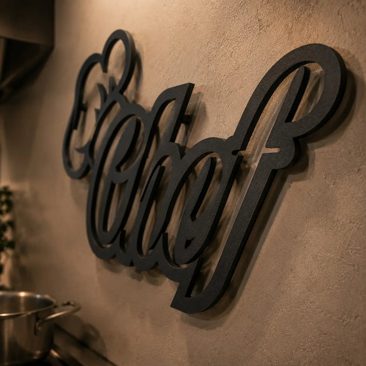 Detailopname van de metalen Chef wanddecoratie. De strakke matzwarte afwerking en afstandhouders zorgen voor een prachtig 3D-effect op de muur.