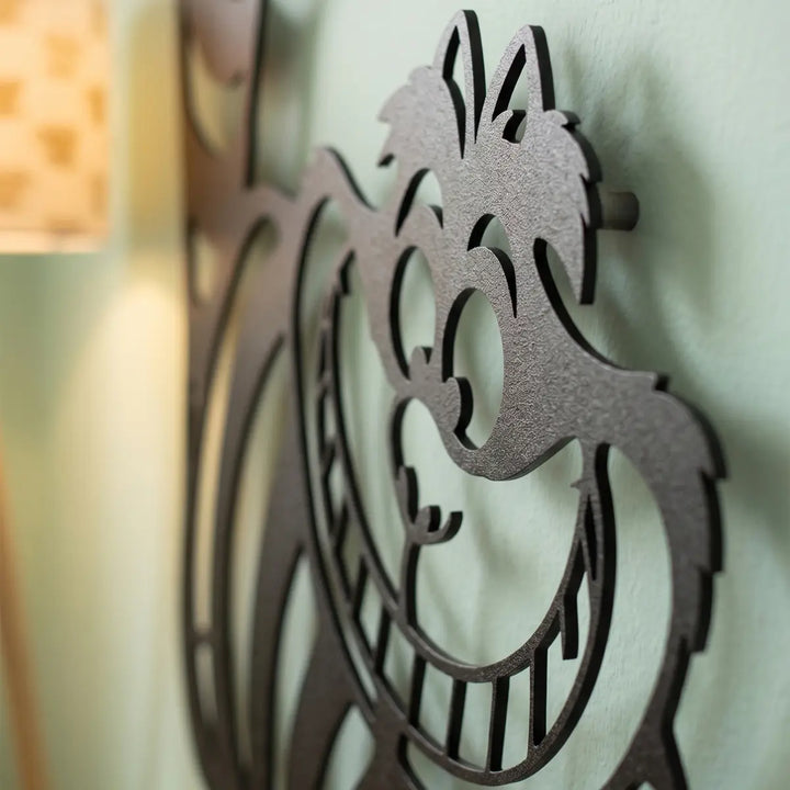 Detailopname van de metalen Cheshire Smile wanddecoratie. Het matzwarte design ve het zwevende 3D-effect creëren een prachtig schaduwspel op de muur.