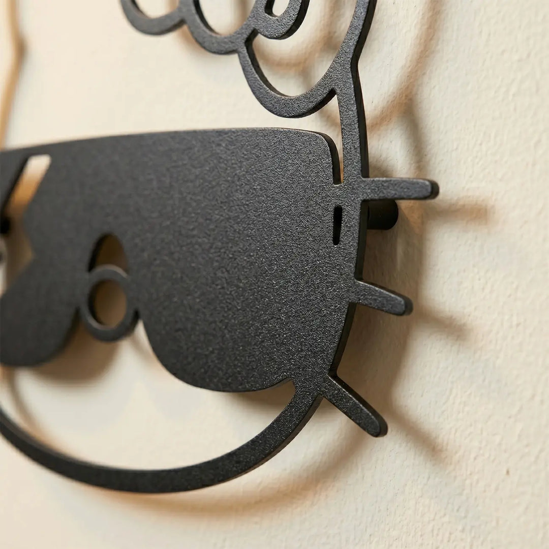 Detailopname van de zwarte metalen Hello Kitty decoratie. De afstandhouders creëren een prachtig zwevend 3D-effect en schaduwspel op de muur.