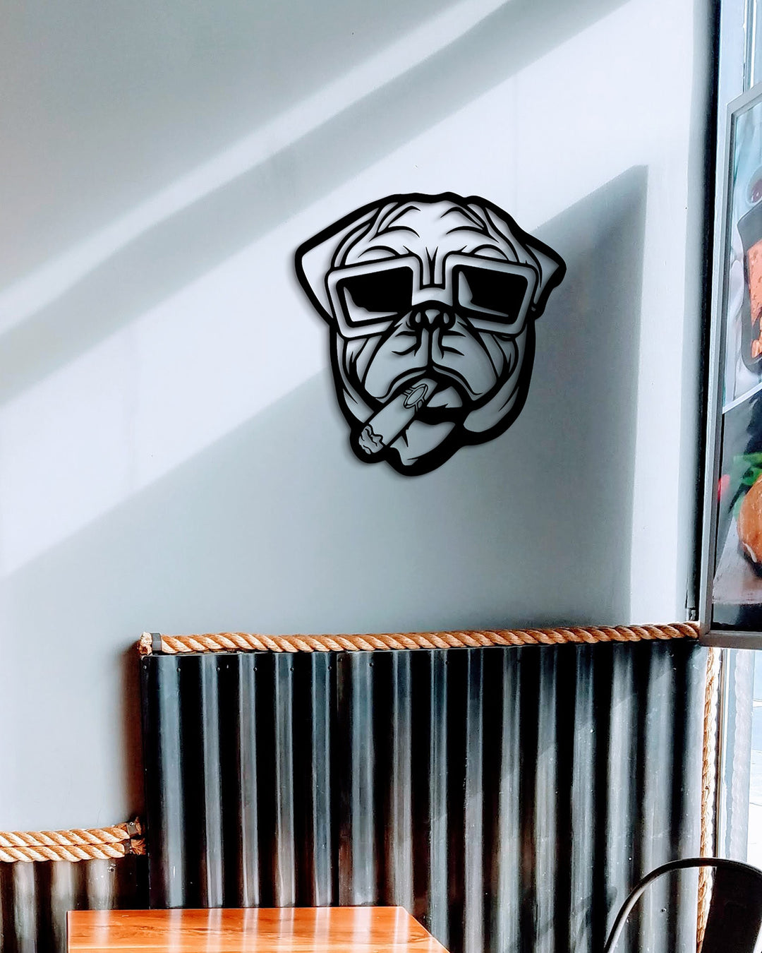 Zwarte metalen pug met zonnebril hangend boven een bank in een moderne, speelse woonkamer.