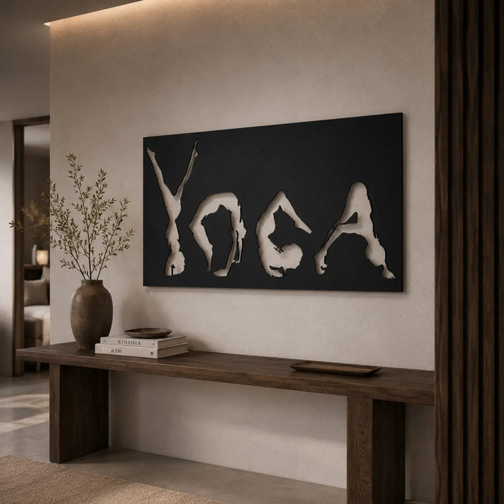 Zwarte metalen wanddecoratie met yoga houdingen en tekst, sfeervol hangend in een lichte hal voor een rustgevende en mindful binnenkomst.