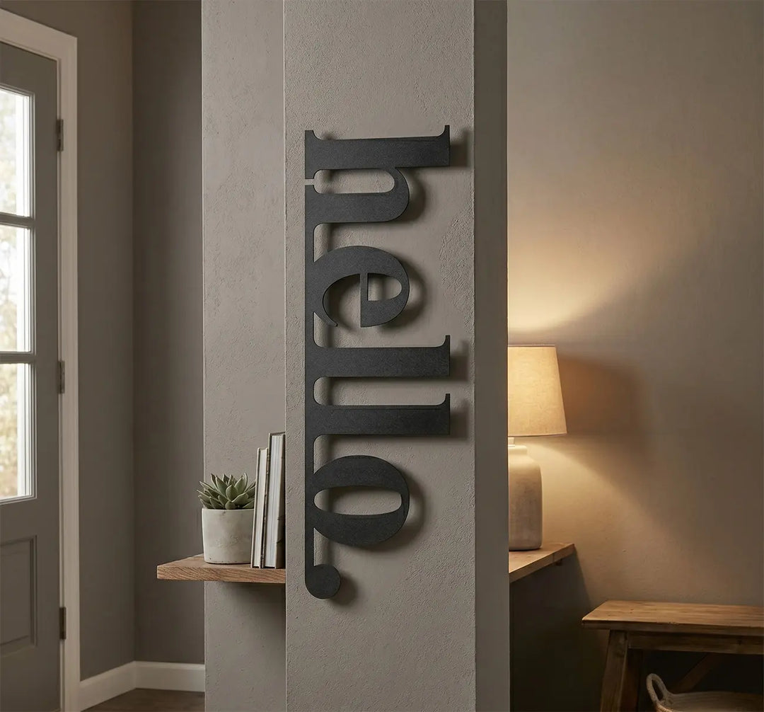 Welkom 'hello' bord van zwart metaal naast de kapstok in de gang. Creëert direct een gastvrije sfeer zodra u het huis binnenstapt.
