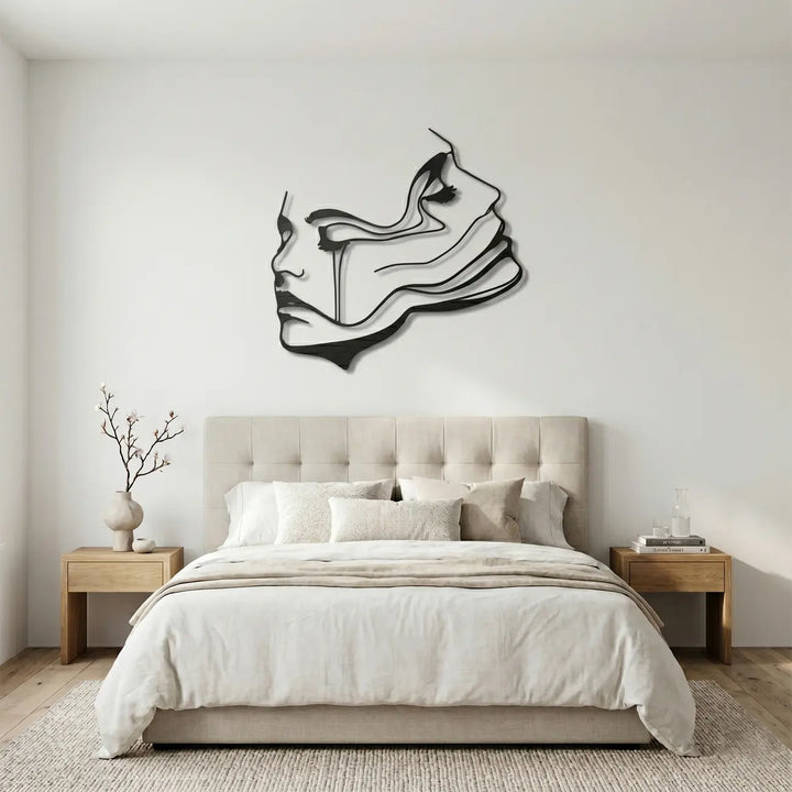 Zwarte metalen wanddecoratie van een abstract gezicht met vloeiende lijnen, modern gestyled boven een bed in een sfeervolle slaapkamer.