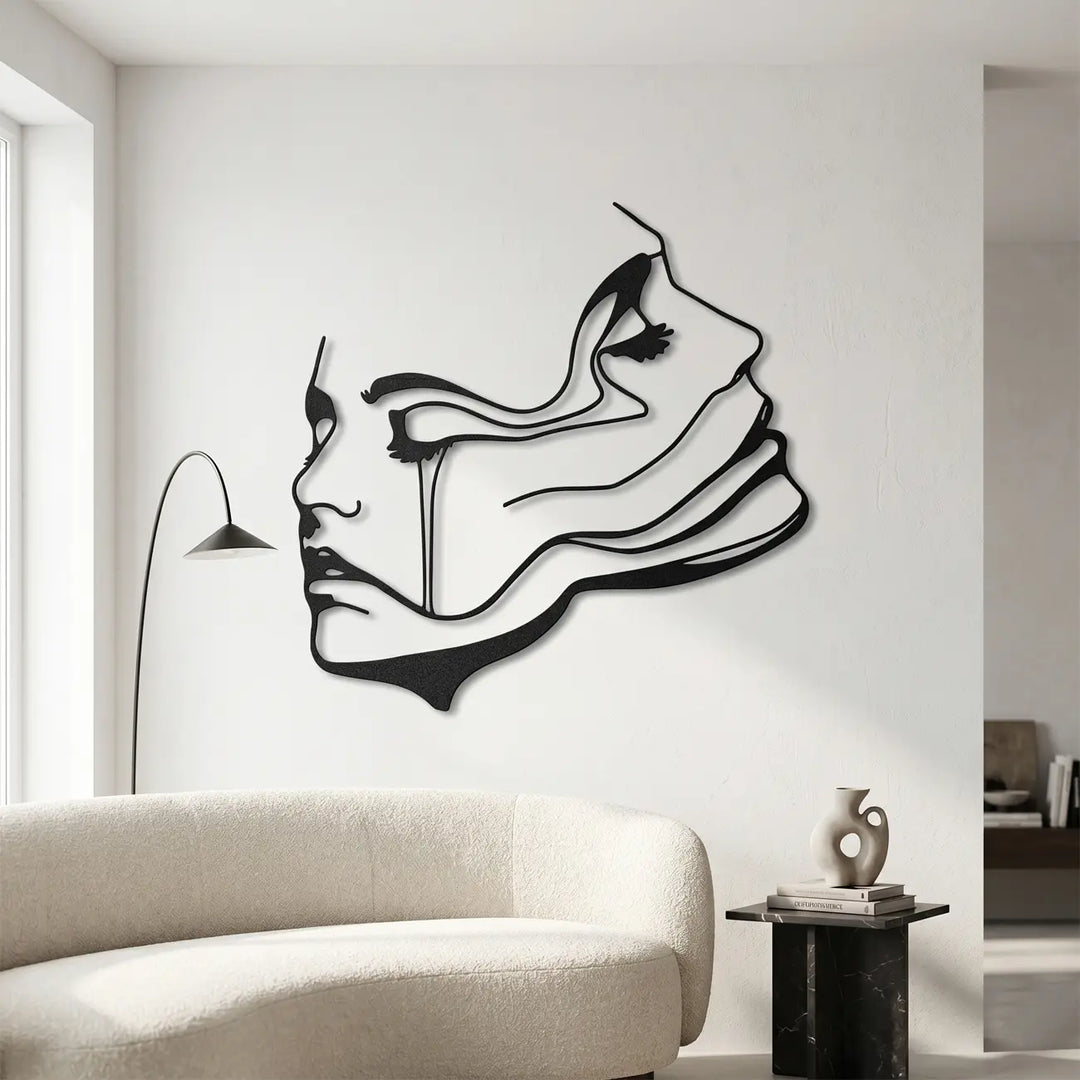 Minimalistische zwarte line-art wanddecoratie van een gezicht, hangend boven een comfortabele bank in een moderne woonkamer.