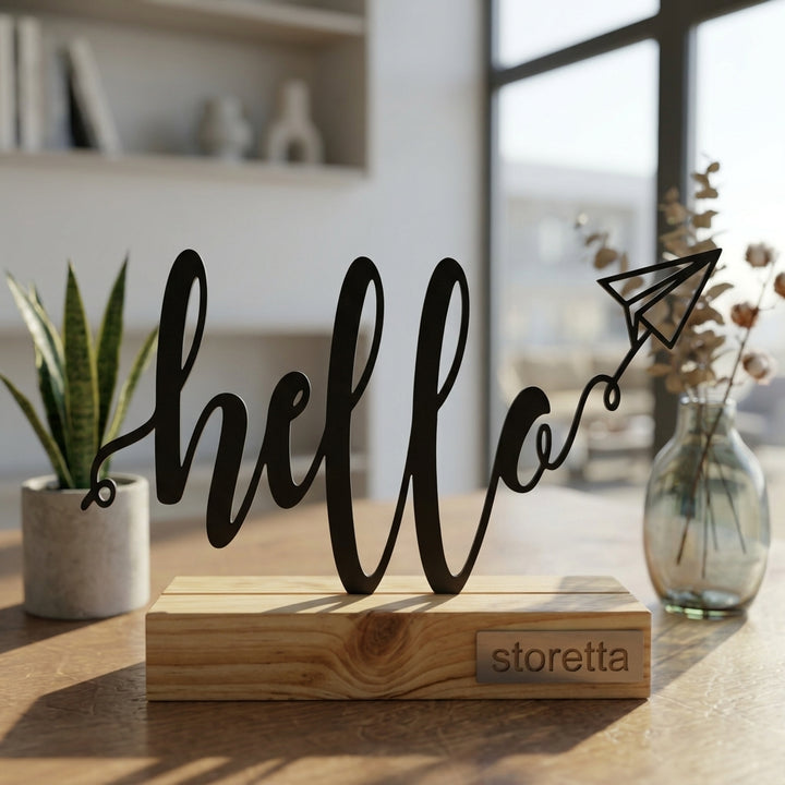 Eigentijdse tafeldecoratie van metaal en hout met speelse Hello tekst en papieren vliegtuigje in daglicht.